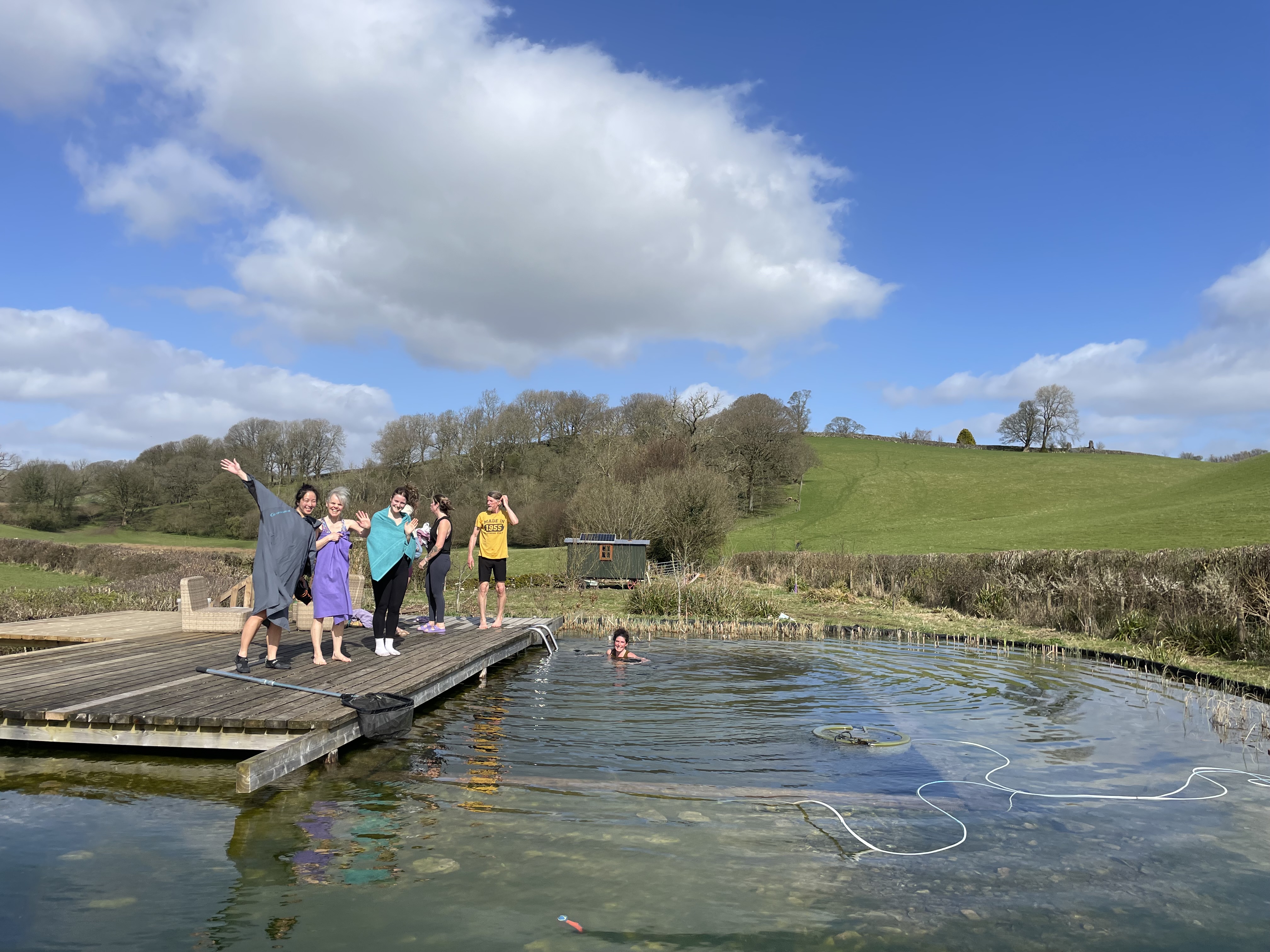 The organic pool at Hot Yoga Cumbria with the Cumbrian hills and setting sun reflected in the water